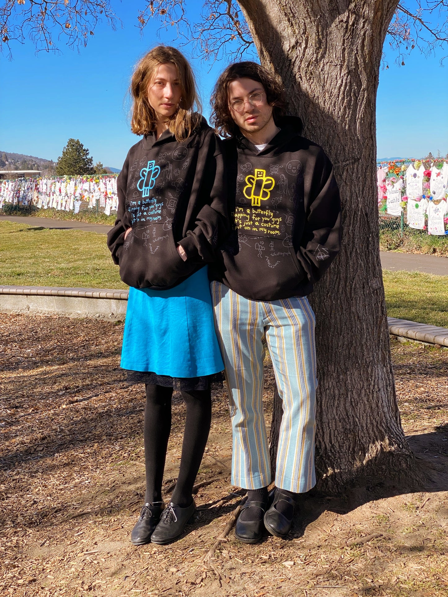 Both hoodies by a tree